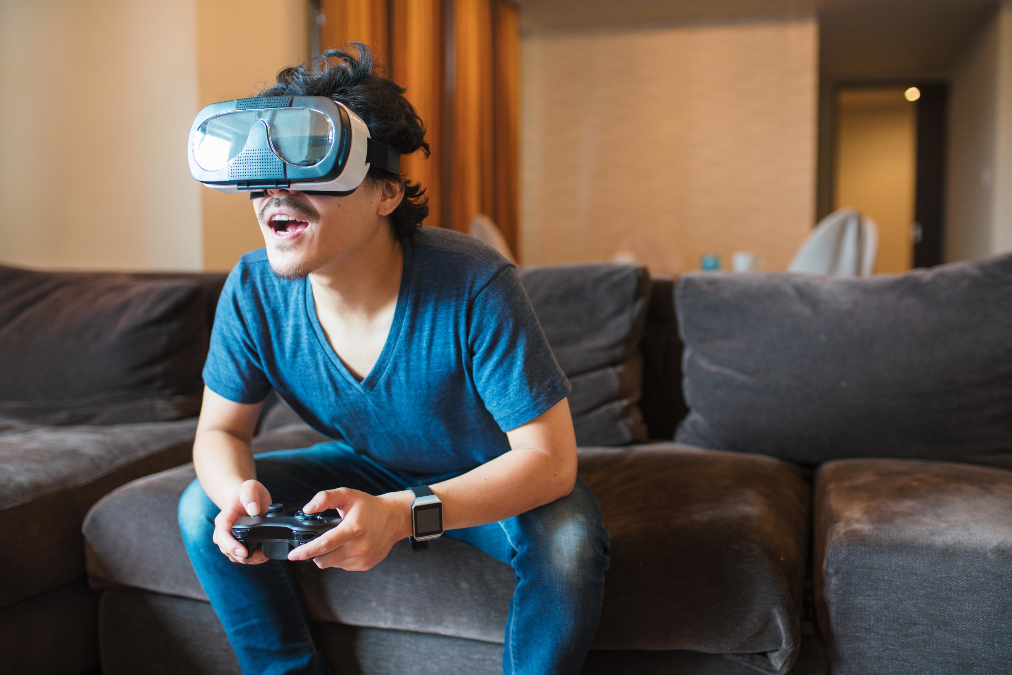 Person using game controller and headset with extension cable.