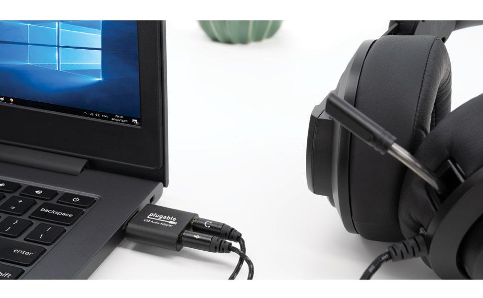 A picture of a Windows Computer with the USB-AUDIO adapter plugged into a USB port. A pair of wired headphones are plugged in to the USB-AUDIO adapter.