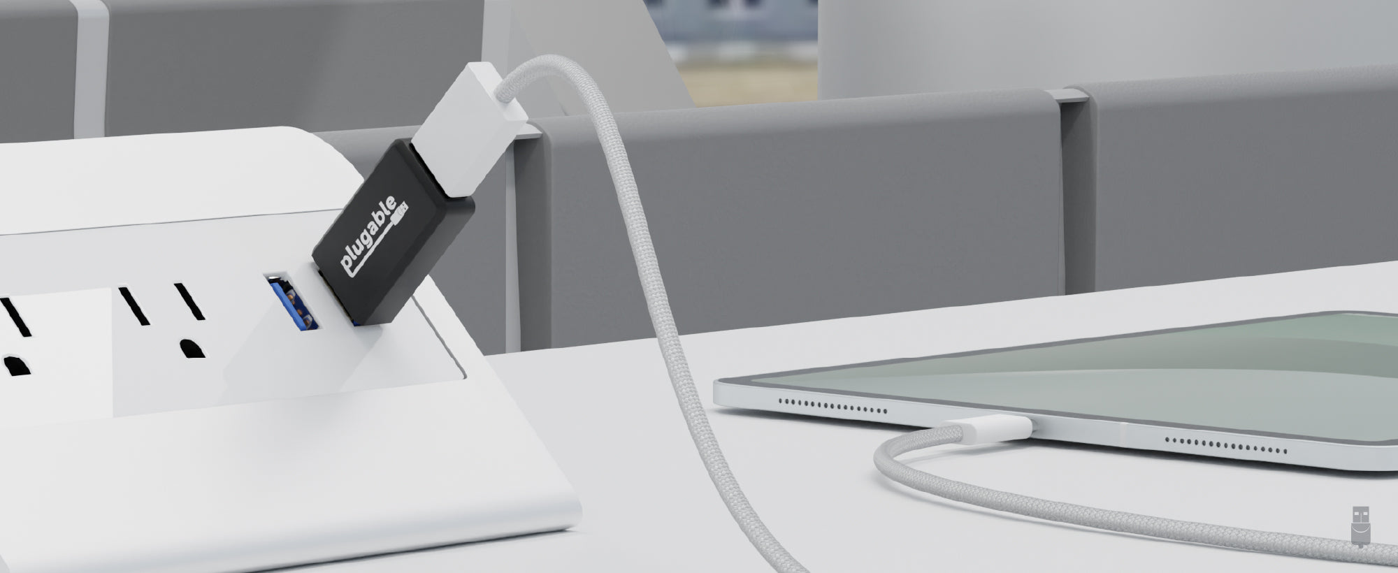 An image of one of the USB-MC1-5X 5-pack. It is plugged into a public USB port, with a tablet plugged into it for secure charging